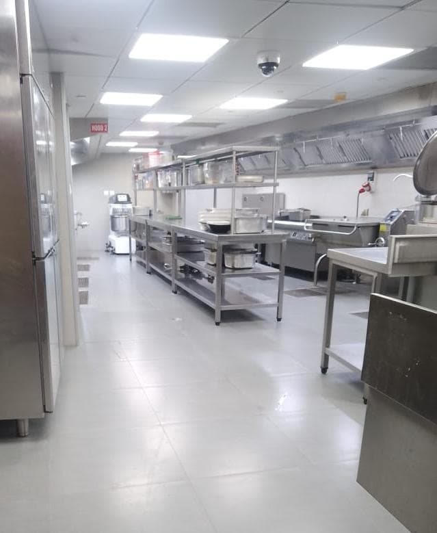 Clean industrial kitchen featuring stainless steel prep tables, shelving units, and professional cooking equipment.