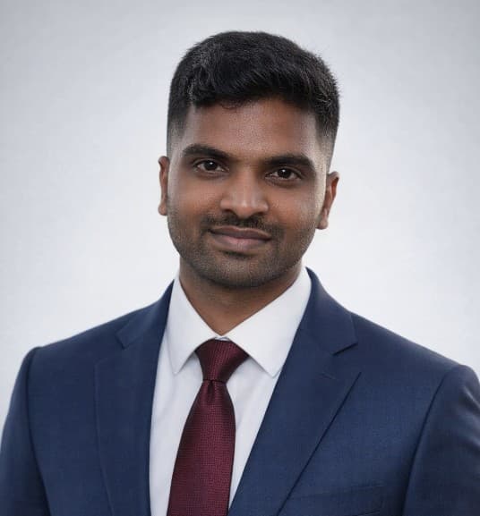 South Asian man wearing a navy blue suit and maroon tie for a professional headshot.
